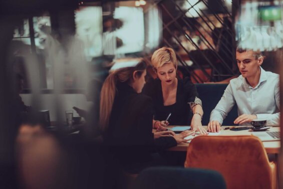 Young professionals sit at a table and do work together.