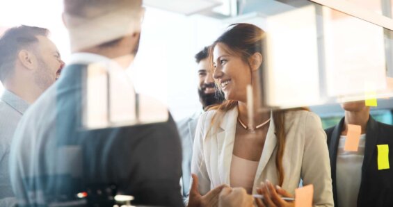 A young business woman smiles as she speaks to a group of her colleagues.