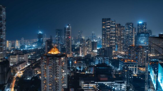 The Mumbai city skyline is brightly lit at night.