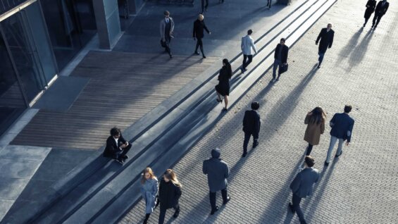 Birds-eye view of business people walking across a cobbled courtyard while commuting to work.