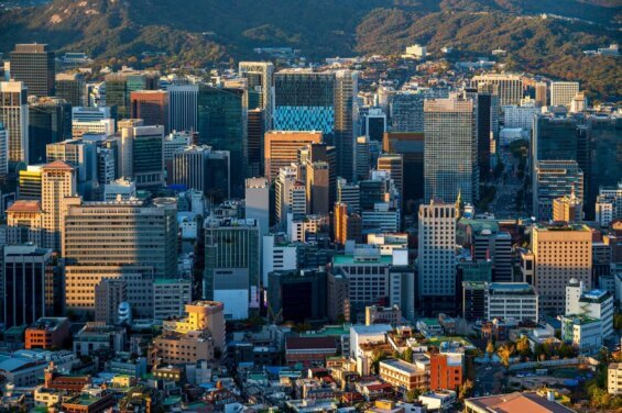 The sun sets on a Seoul cityscape with high rise office buildings and skyscrapers.