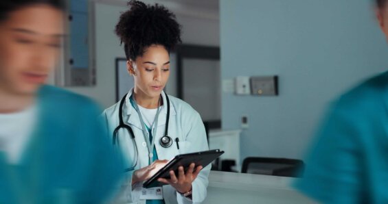 A young doctor at a hospital consults a tablet.